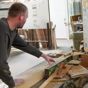 Ein Schreiner arbeitet an einer Holzbearbeitungsmaschine in einer modernen Werkstatt.