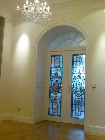 Doppeltür mit verziertem Buntglas und Kristallleuchter in elegantem Wohnzimmer.