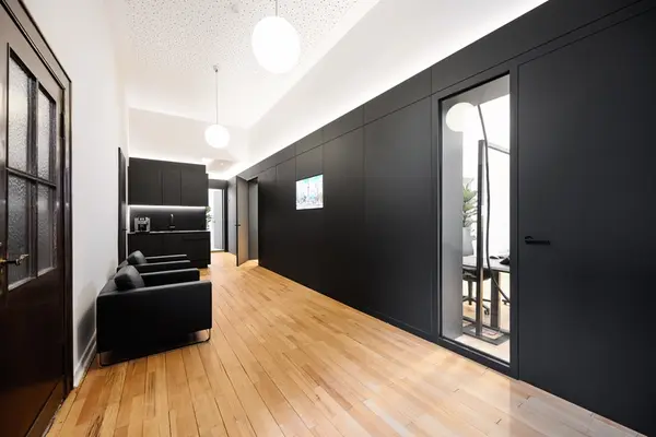 Modernes Büro mit schwarzer Wandverkleidung, Wartebereich und hellem Holzboden.