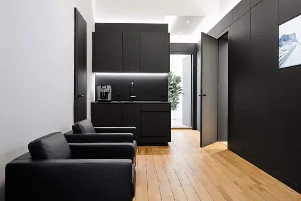 Modern eingerichtete schwarze Büroküche mit Ledersesseln und Holzfußboden.