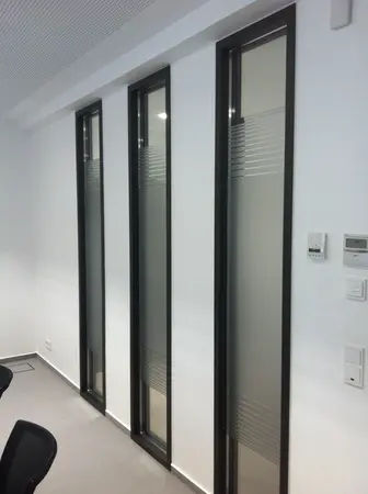 Drei schmale, moderne Glasfenster mit Milchglasstreifen in einer weißen Bürowand.